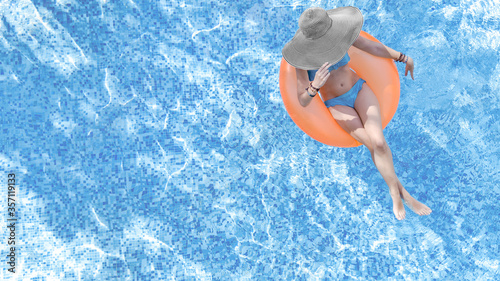 Beautiful woman in hat in swimming pool aerial top view from above, young girl in bikini relaxes and swims on inflatable ring donut and has fun in water on family vacation, tropical holiday resort 