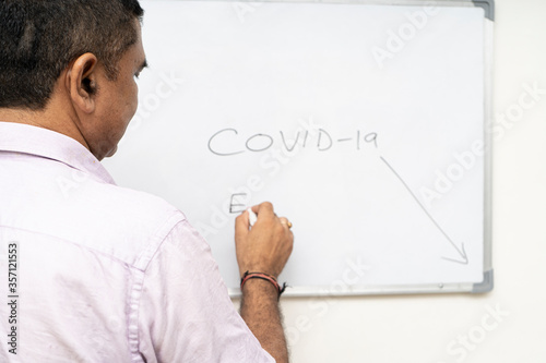 teacher teaching about corona virus to students, Covid-19 written on white board.