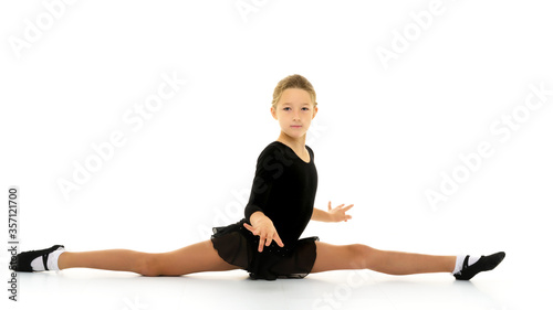 Slender girl gymnast doing the twine. The concept of children's sport.