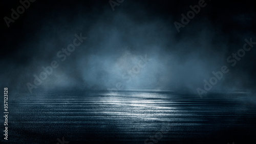 Dark dramatic abstract scene background. Neon glow reflected on the pavement. Smoke  smog and fog. Dark street  wet asphalt  reflections of rays in the water. Abstract dark blue background. 