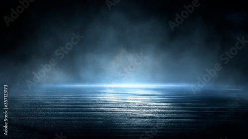 Dark dramatic abstract scene background. Neon glow reflected on the pavement. Smoke, smog and fog. Dark street, wet asphalt, reflections of rays in the water. Abstract dark blue background. 
