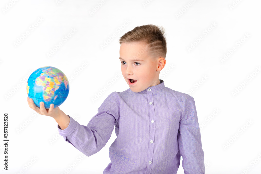 Playful young caucasian school boy holding a globe on white studio background.Boy is surprised shows at globe laughing Playful young caucasian school boy holding a globe on white studio background.Boy is surprised shows at globe laughing