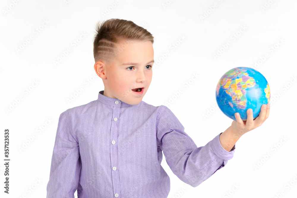 Playful young caucasian school boy holding a globe on white studio background.Boy is surprised shows at globe laughing Playful young caucasian school boy holding a globe on white studio background.Boy is surprised shows at globe laughing