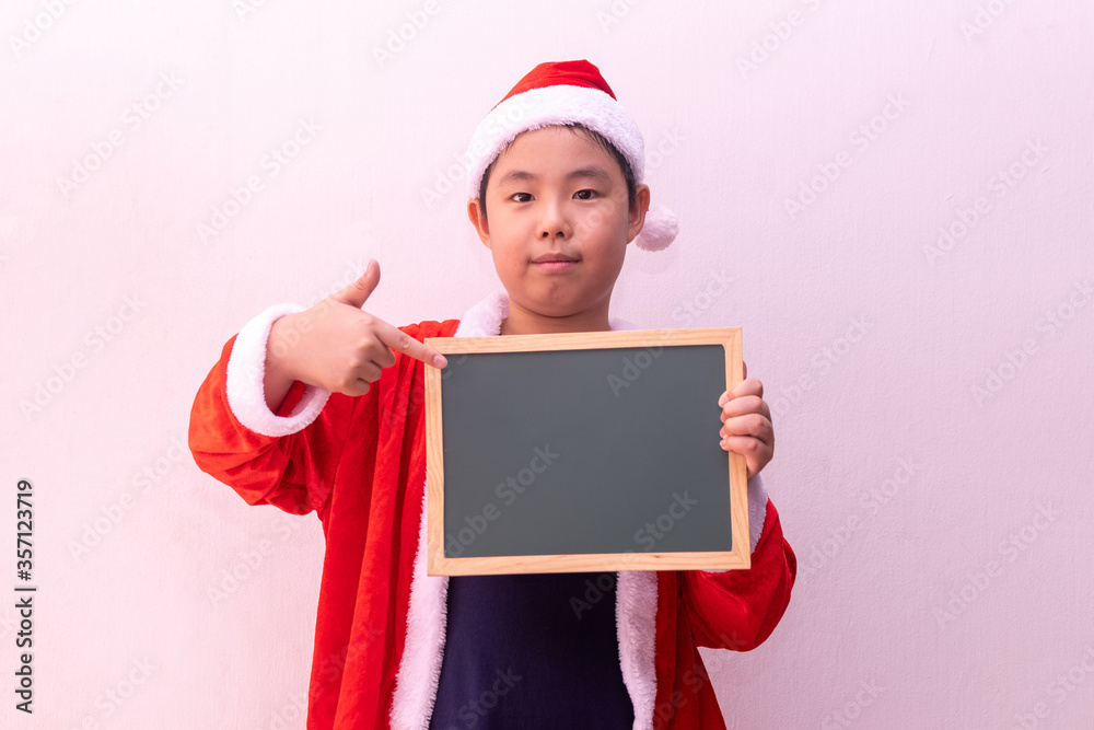 Asian boy in Santa Claus clothes holding empty board. Merry christmas Asian boy in Santa Claus clothes holding empty board. Merry christmas