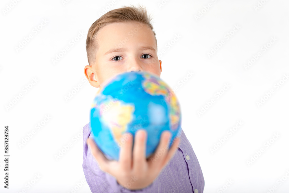 Playful young caucasian school boy holding a globe on white studio background.Boy is surprised shows at globe laughing Playful young caucasian school boy holding a globe on white studio background.Boy is surprised shows at globe laughing
