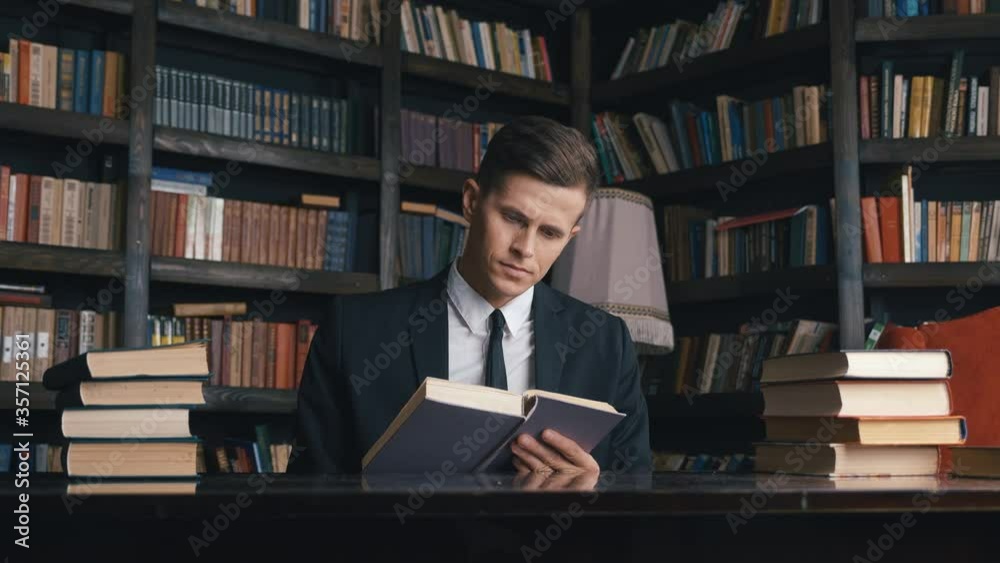 Businessman in classical suit sitting in library reading book. Businessman in classical suit sitting in library reading book.