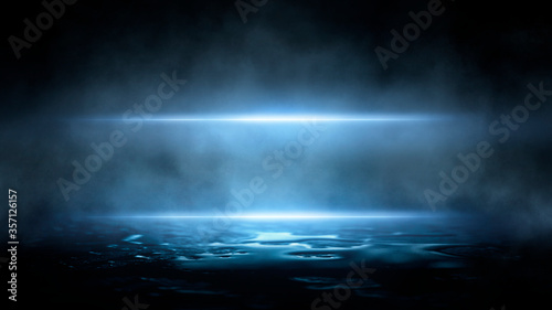 Dark dramatic abstract scene background. Neon glow reflected on the pavement. Smoke, smog and fog. Dark street, wet asphalt, reflections of rays in the water. Abstract dark blue background. 