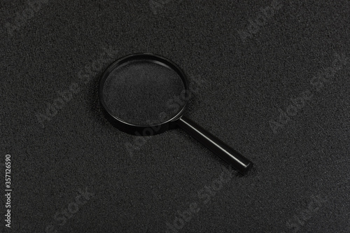 Black magnifying glass on black background. Magnifier