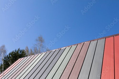 Colorful roof of a single-family house. Blue clear sky during spring morning.