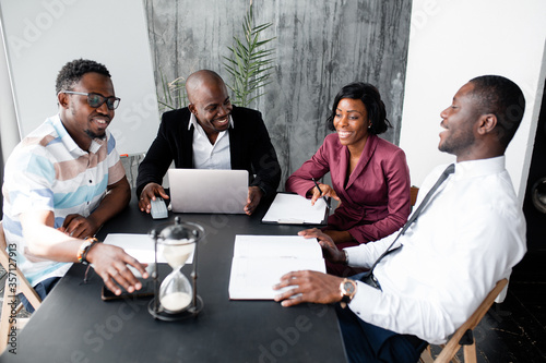 Dark skinned members of the board of directors discuss the company's development strategy in office