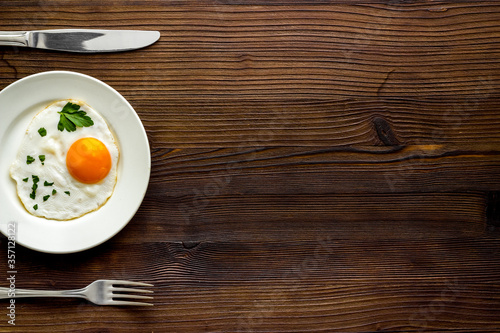 Fried eggs on plate - dark wooden dinner table from above copy space
