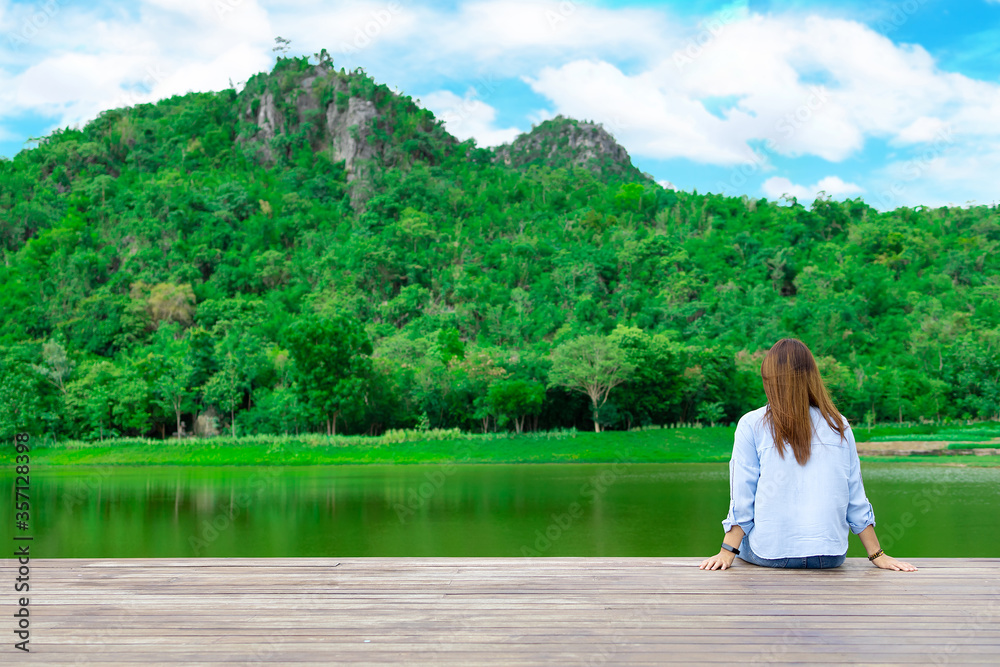 Peaceful lifestyle shot of woman sitting on dock Lake. Sit and rest comfortably on your vacation.
