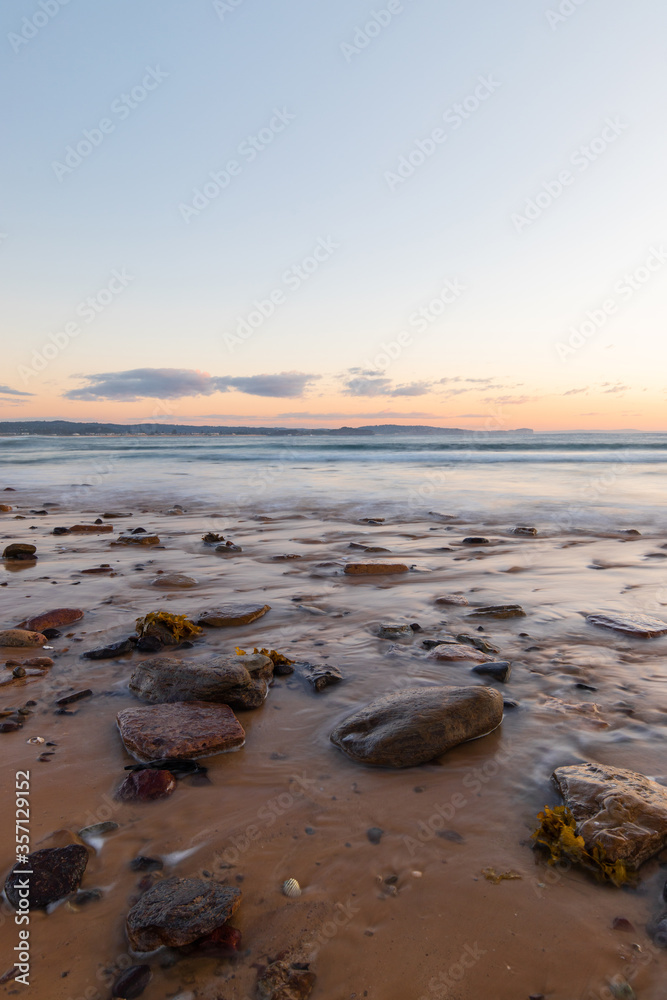 Water flowing around the rocks on the sand.