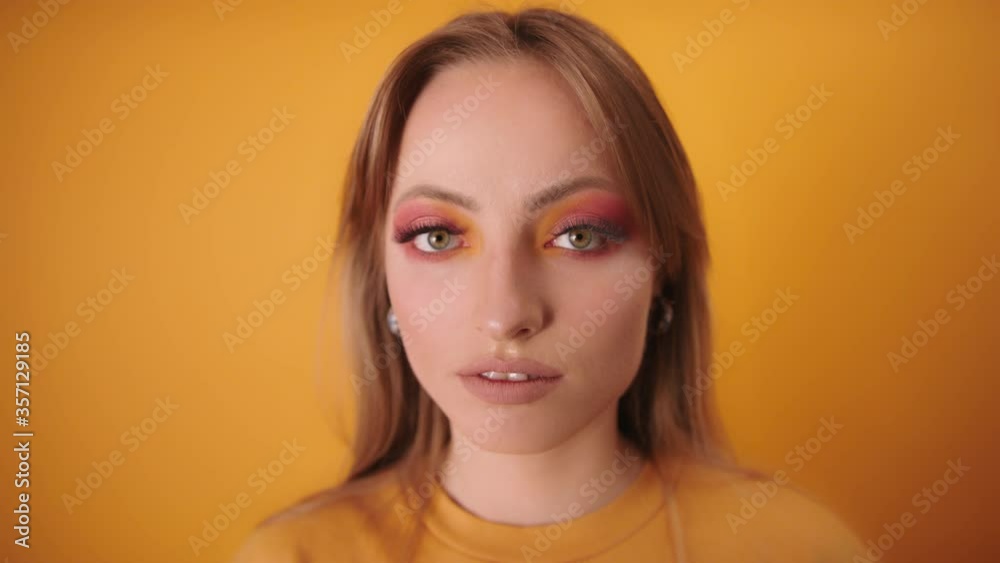 Portrait woman looks intensely on camera. CloseUp isolated on yellow