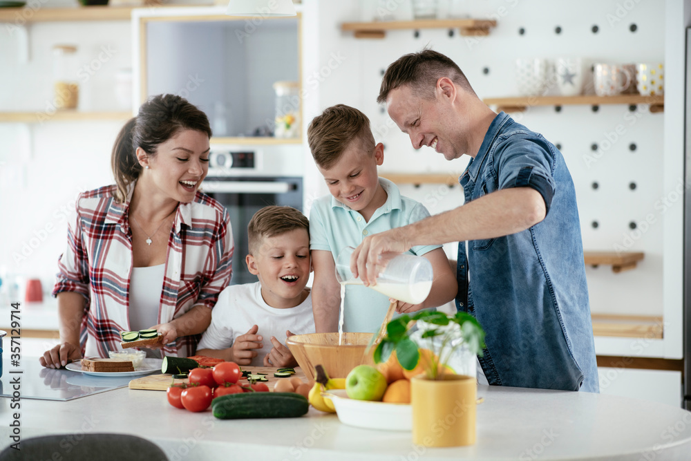 Mother and father making breakfast with sons. Young family preparing delicious food in kitchen. Mother and father making breakfast with sons. Young family preparing delicious food in kitchen.