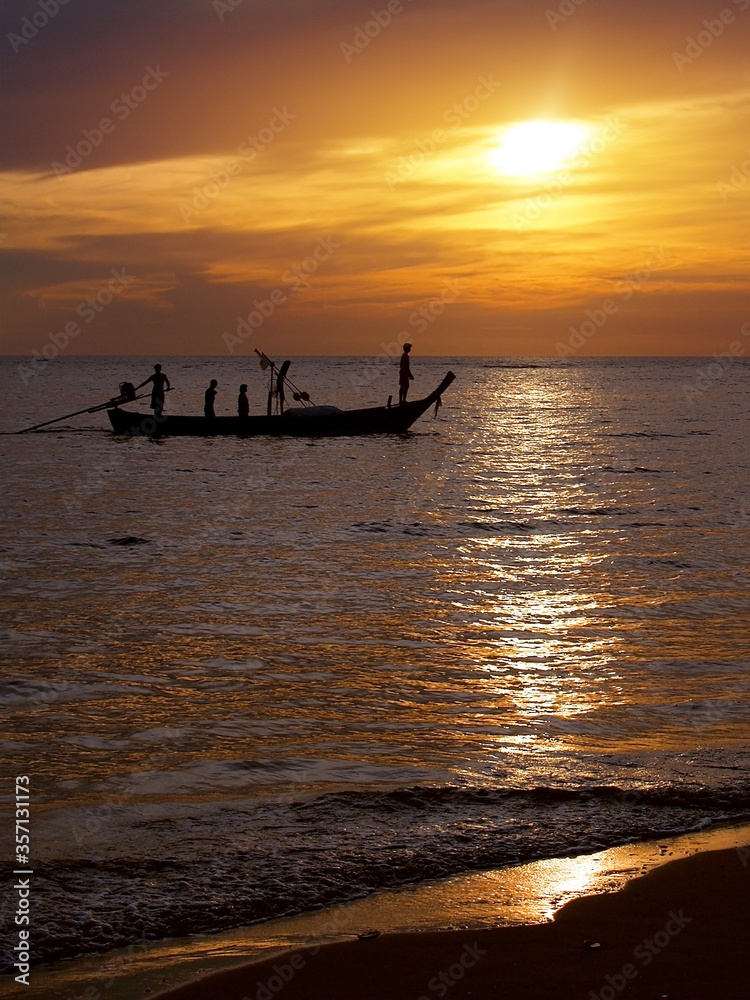 silhouette unidentified local fisherman go fishing by small traditional long tail boat in evening time with sunset