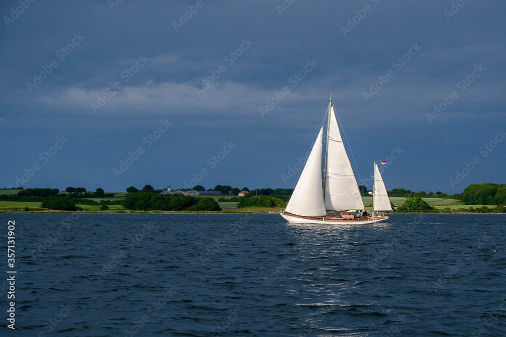 Obraz premium Segelyacht, Ketsch in der Sonne vor dunklen Wolken