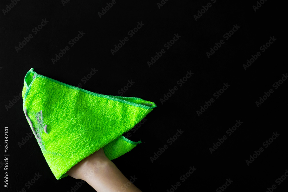 Cleaning the house. Wipe off the dust with a green rag from a dirty surface. A lot of dust on a rag.