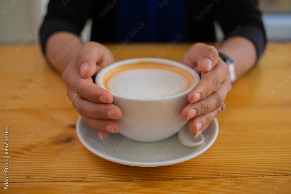 Hand Women put a Latte arts coffe hot coffee on wooden table.barista love art concept. Hand Women put a Latte arts coffe hot coffee on wooden table.barista love art concept.