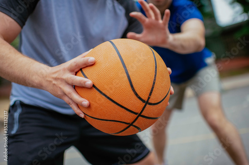 Close up of hands holding ball. Friends playing basketball in the park.