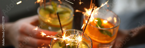 Sticker Young group friends hold in hand fruit cocktail with sparkler decoration