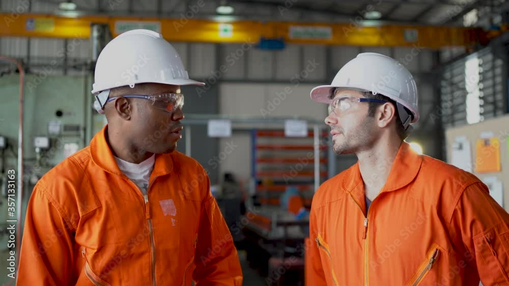 Two technicians or engineer workers shake hands together that one as manager and discuss about their work in the factory workplace.
