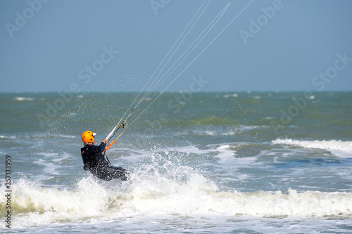 Lone kitesurfer sailing through waves © Roy