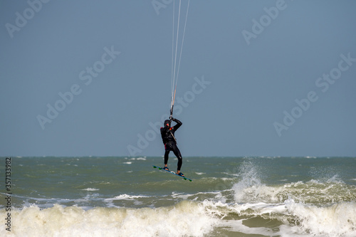 Lone kitesurfer jumping on the sea