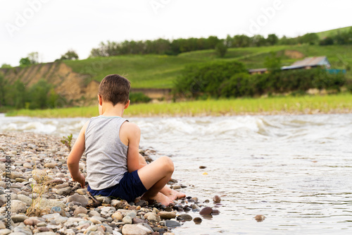 a village boy on the river Bank collects stones © Гульнара Мандрыкина