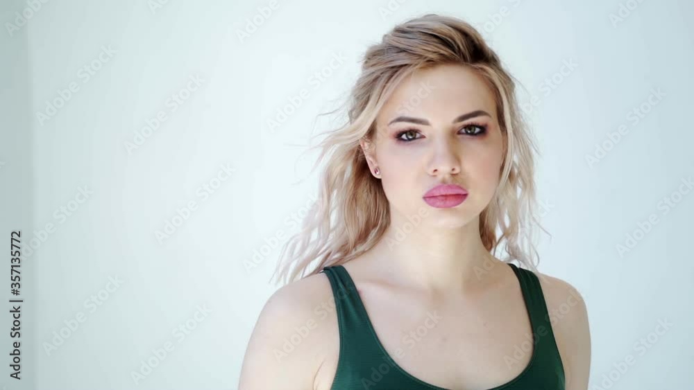 Close up portrait of sport blonde woman with makeup. The woman goes forward and looking at camera. Female sensuality beauty, fitness training. Slow motion, white background Close up portrait of sport blonde woman with makeup. The woman goes forward and looking at camera. Female sensuality beauty, fitness training. Slow motion, white background
