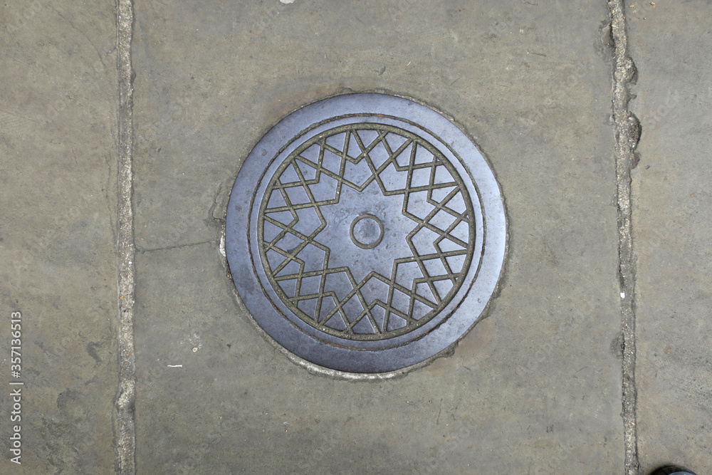 round manhole cover on the street, decorated with a star pattern