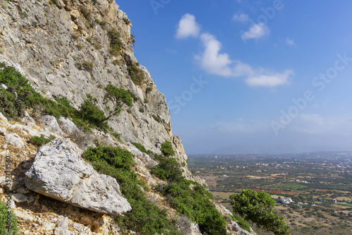 Picturesque slope of rocky mountain at highlands with valley underneath. Hiking in mountains. Mountain area with village in valley.