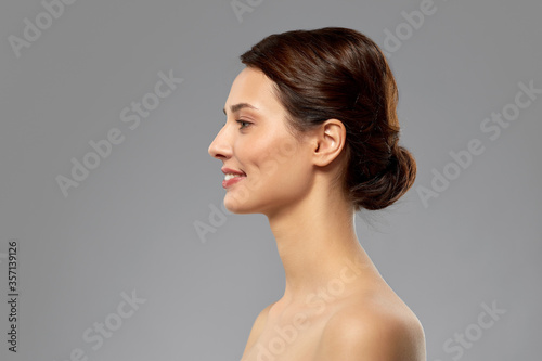 beauty, bodycare and people concept - profile of beautiful young woman with bare shoulders over grey background