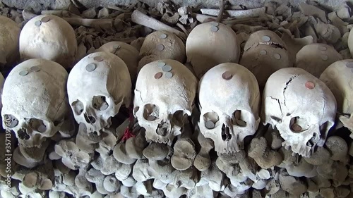 Ossuary with stacks of skulls and bones inside the ancient Fontanelle cemetery in Naples, Italy, located in a cave in the tuff hill and associated with the cult of the dead.