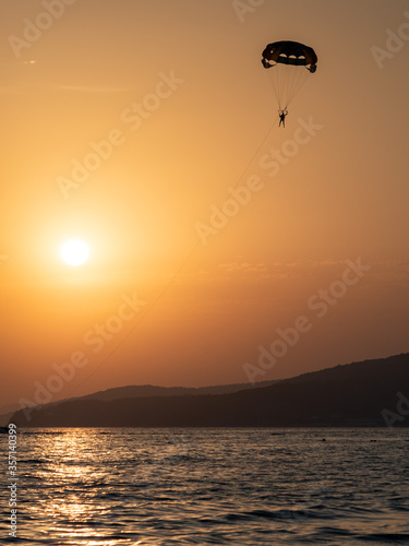 Parachute flight on the background of the sunset by the sea.
