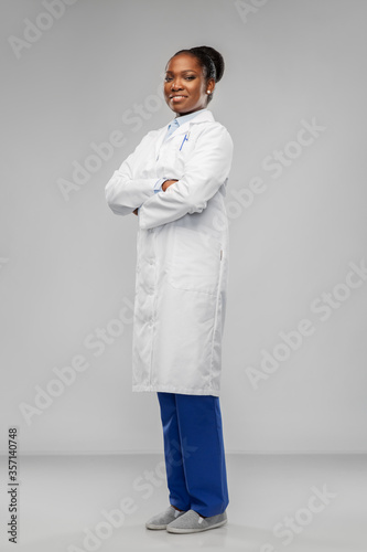 medicine, profession and healthcare concept - smiling african american female doctor or scientist in white coat with crossed hands over grey background photo