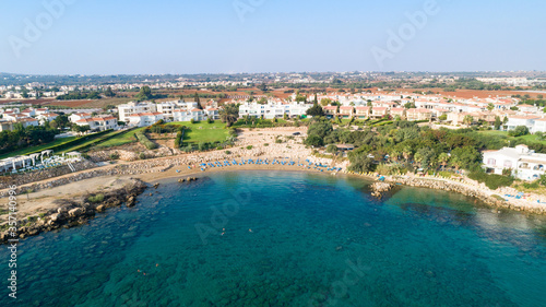 Aerial bird's eye view of Sirena beach in Protaras, Paralimni, Famagusta, Cyprus. The famous Sirina bay tourist attraction with sunbeds, golden sand, restaurant, people swimming in the sea from above. © f8grapher