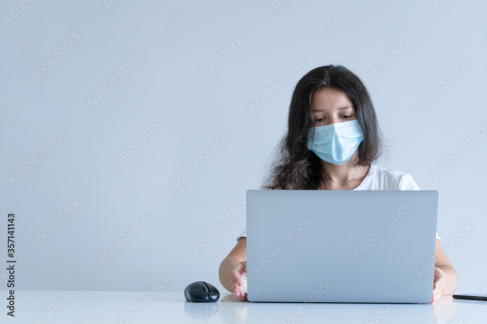 The girl works from home during quarantine. Corona virus pandemic. A girl in a surgical mask works on a laptop and drinks coffee. Distant work The girl works from home during quarantine. Corona virus pandemic. A girl in a surgical mask works on a laptop and drinks coffee. Distant work