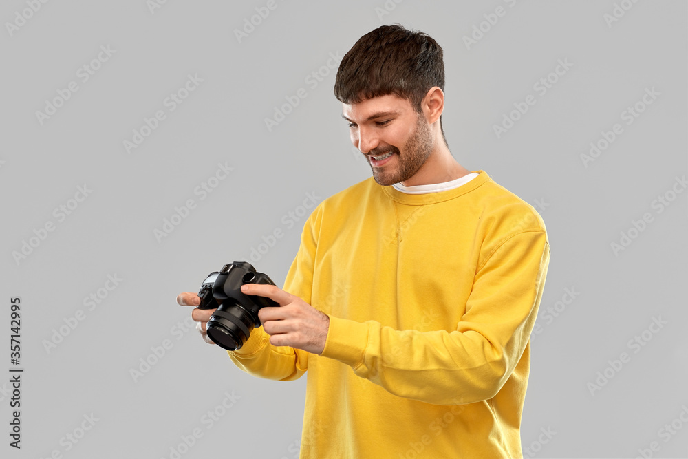 photography and people concept - smiling young man or photographer in yellow sweatshirt with digital camera over grey background photography and people concept - smiling young man or photographer in yellow sweatshirt with digital camera over grey background