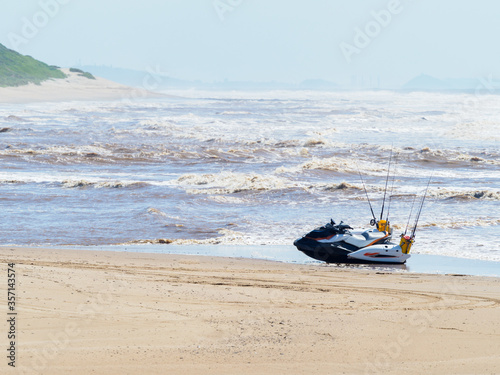 A jet ski loaded with fishing gear parked on a lonely sandy beach.
