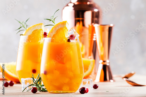 Orange cocktail with cranberry, rosemary and ice. Alcoholic, non-alcoholic drink beverage, copper bar tools, copy space