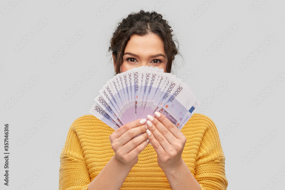 finance, investment and saving concept - young woman covering her face with fan of euro money over grey background finance, investment and saving concept - young woman covering her face with fan of euro money over grey background