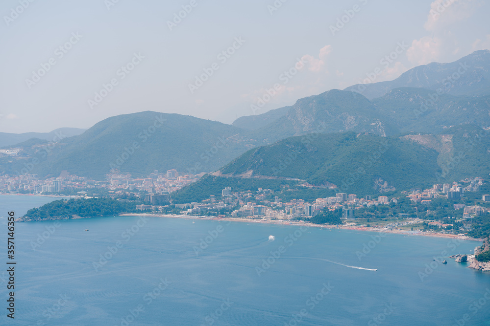 Budvan coast in Montenegro. Coastline of the cities of Rafaelovici and Beechichi. Long beach with sunbeds and umbrellas. Hotels, villas and apartments on the coast.