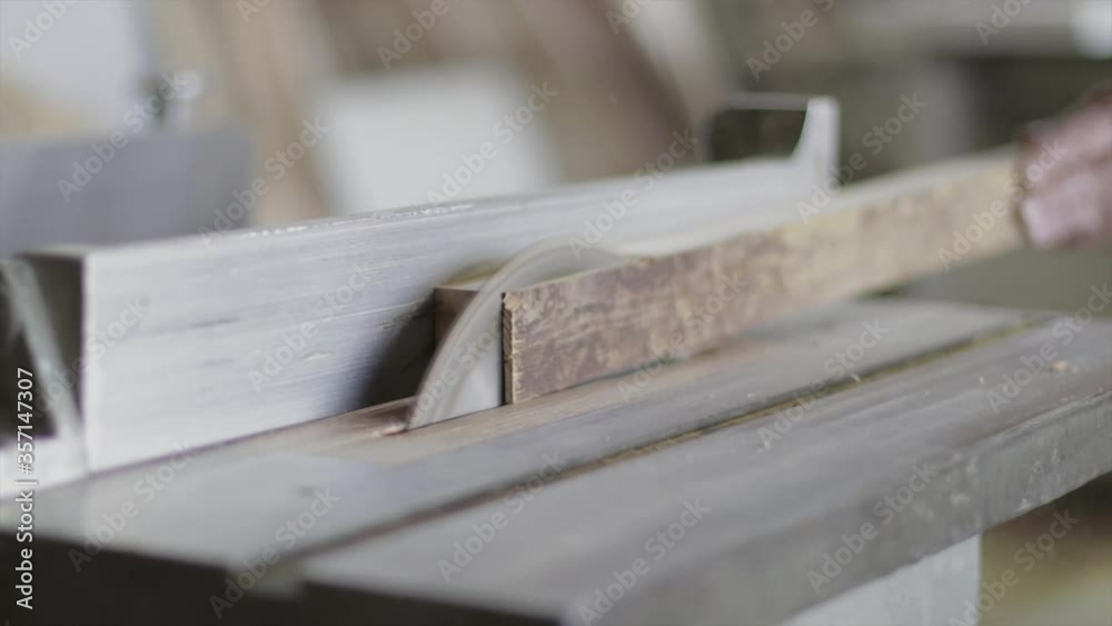 Electric saw cutting wood plank in a carpenter's shop. Professional woodwork equipment. Electric saw cutting wood plank in a carpenter's shop. Professional woodwork equipment.