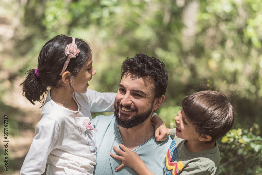 Father with son and daughter playing in pine forest Father with son and daughter playing in pine forest