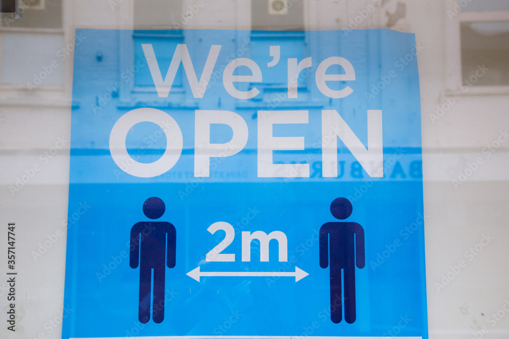 We're open 2 metres apart sign. On the high street, as shops prepare to reopen on the 15th June following the Coronavirus Pandemic We're open 2 metres apart sign. On the high street, as shops prepare to reopen on the 15th June following the Coronavirus Pandemic