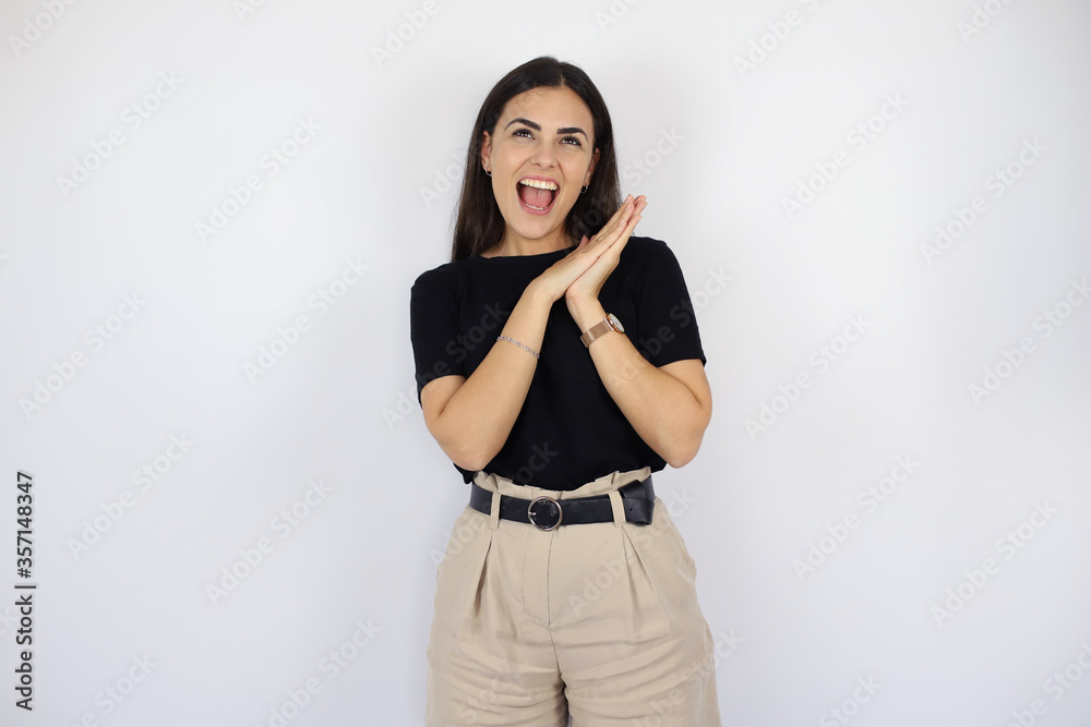Young beautiful woman standing over white isolated background smiling and surprised with her hands in the air Young beautiful woman standing over white isolated background smiling and surprised with her hands in the air