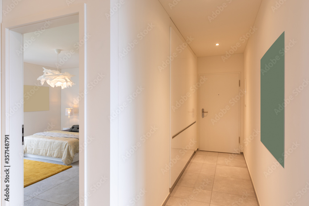 Interior of a long corridor of an apartment. At the bottom a closed door Interior of a long corridor of an apartment. At the bottom a closed door