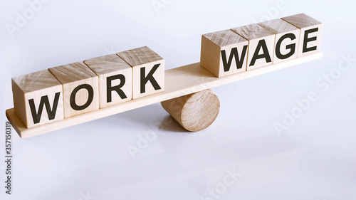 Wooden seesaw representing imbalance between WORK and WAGE isolated over white background
