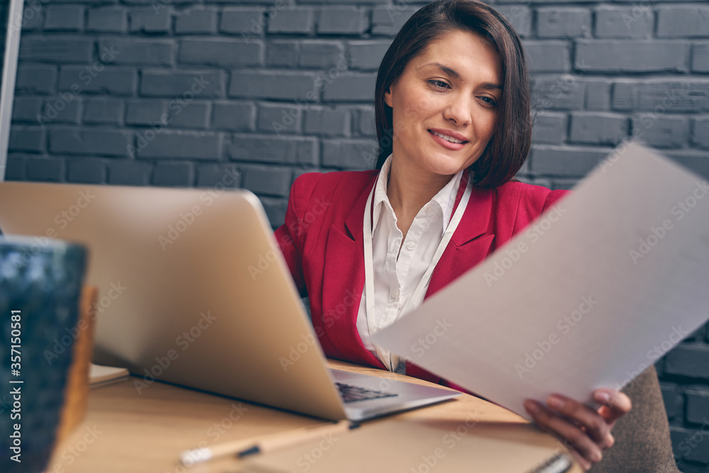 Charming young female person looking at her documents Charming young female person looking at her documents